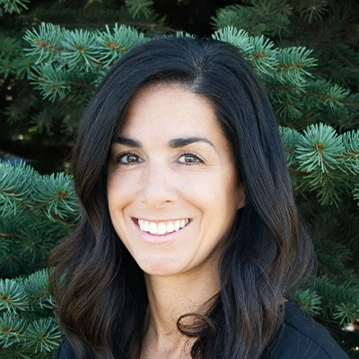 Billing Assistant Manager Cathy Smiling Outdoors In Front Of Pine Tree