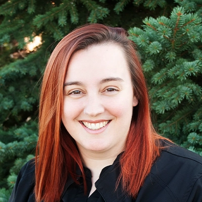 Massage Therapist Jennifer Smiling Outdoors In Front Of Pine Tree