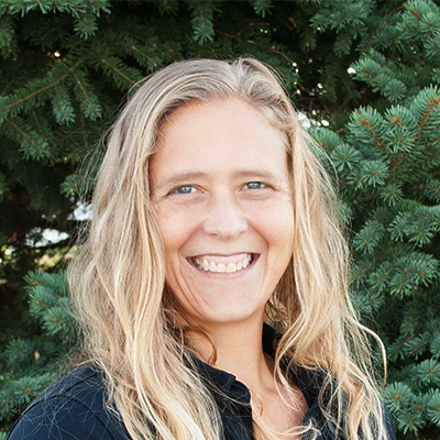 Nurse Practitioner Sierra Burnett Smiling Outdoors In Front Of Pine Tree